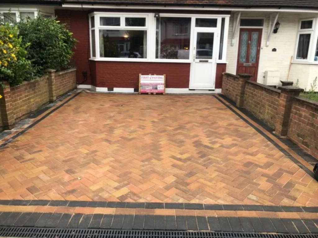 Paving company in Enfield completing a neat block paving driveway with brick retaining walls in front of a residential house