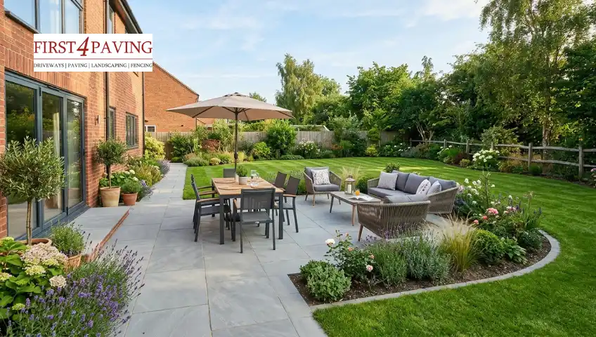 A beautiful stone slab patio with premium outdoor dining furniture and integrated garden borders, showcasing a high-end finish that impacts a new patio cost.