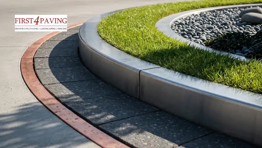 A close-up shot of a modern, curved driveway edging design with stainless steel borders, a grass strip, and dark pebbles.