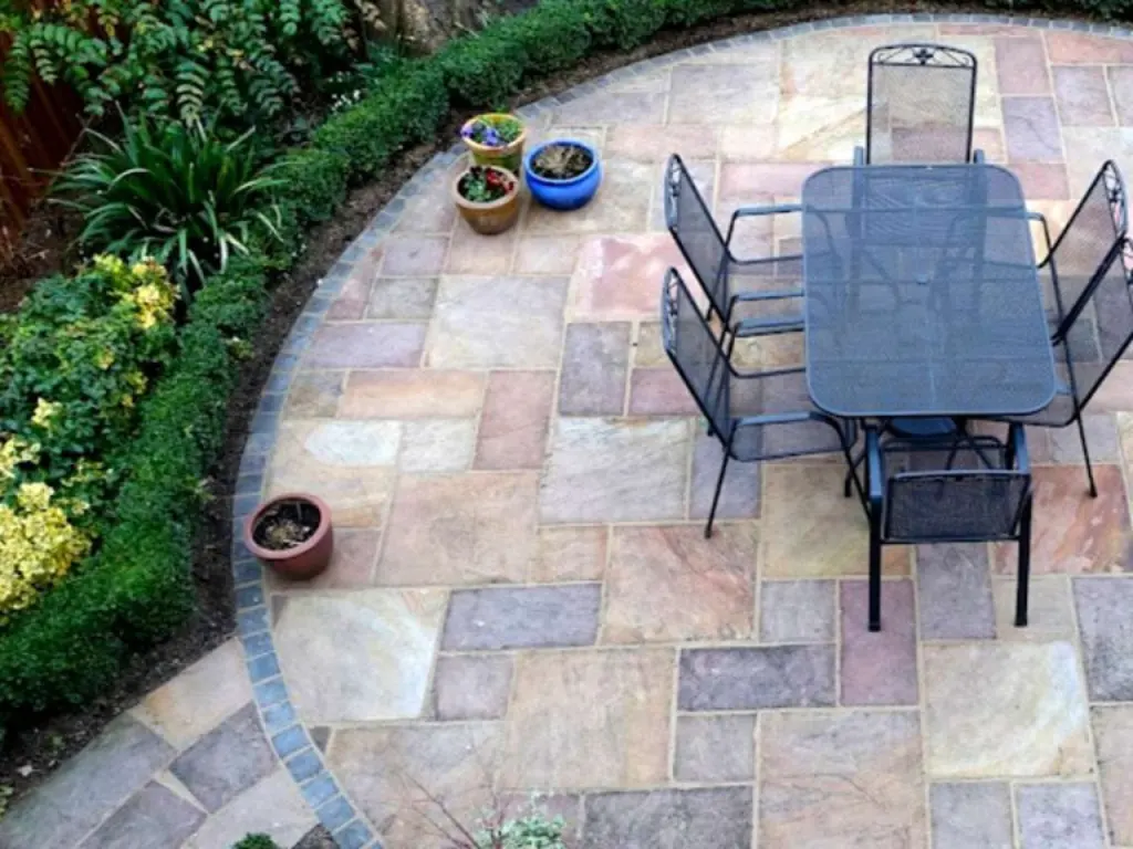 Paving Company in Enfield laying a curved indian sandstone patio with a neat block border and outdoor dining set