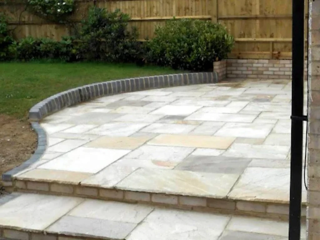 Paving contractors in Enfield building a stone patio split level terrace with brick steps next to a wooden garden fence